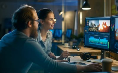 Beautiful Female and Handsome Male Video Editors Discuss Footage They're Working On. They Enjoy Working Together in a Cozy Creative Studio.